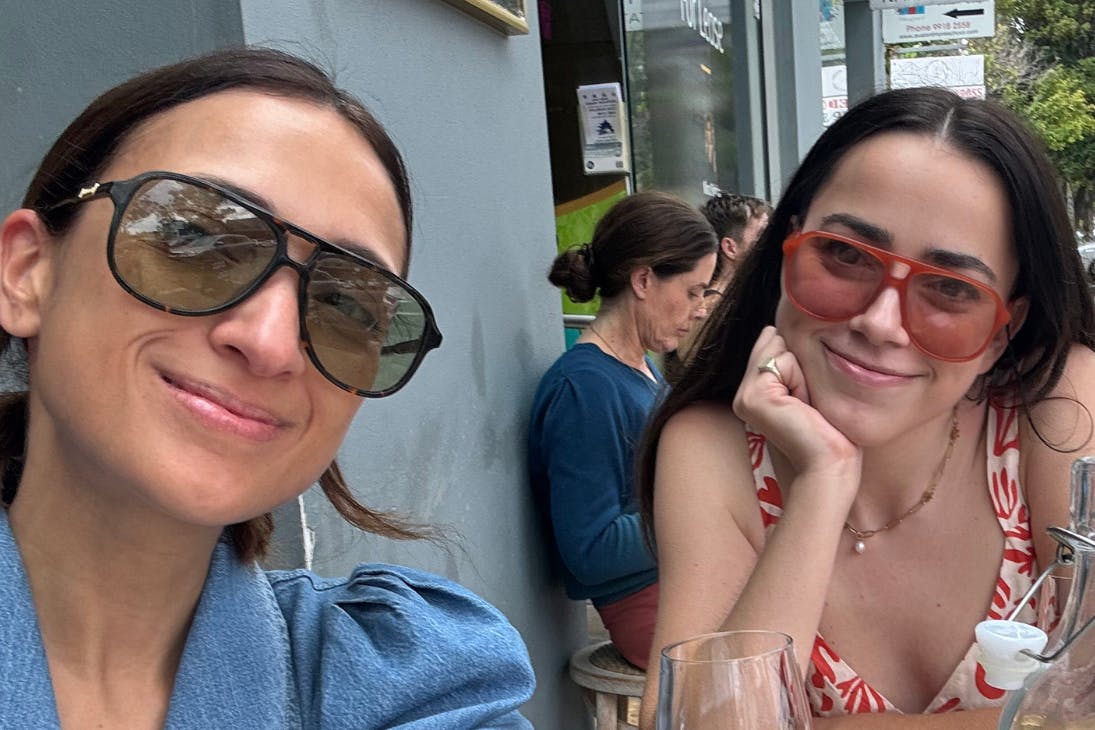 Two women wearing sunglasses and smiling